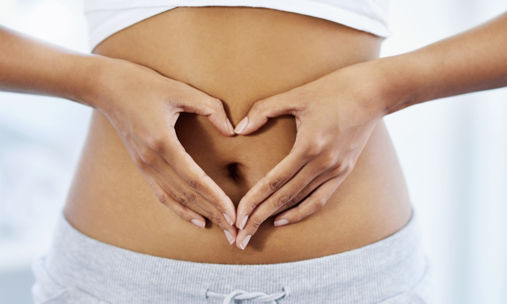 Woman with hands forming a heart over her stomach indicating care for her gut health via pre-biotics and healthy eating.